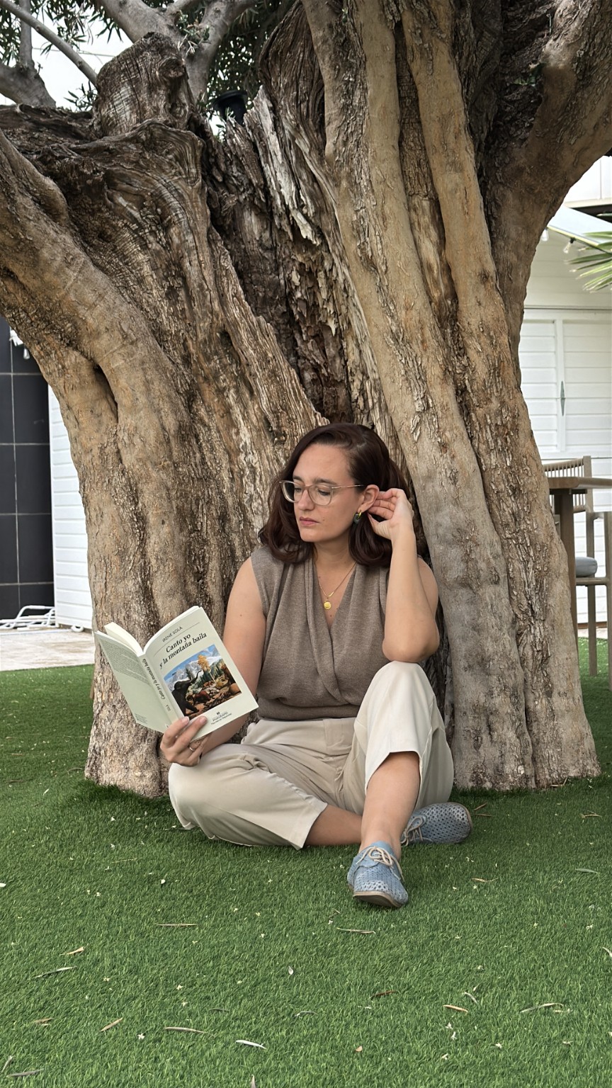 Maribel Barrau leyendo sentada bajo un árbol